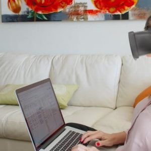 mulher com o óculos virtual no sofá digitando no laptop