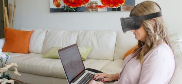 mulher com o óculos virtual no sofá digitando no laptop